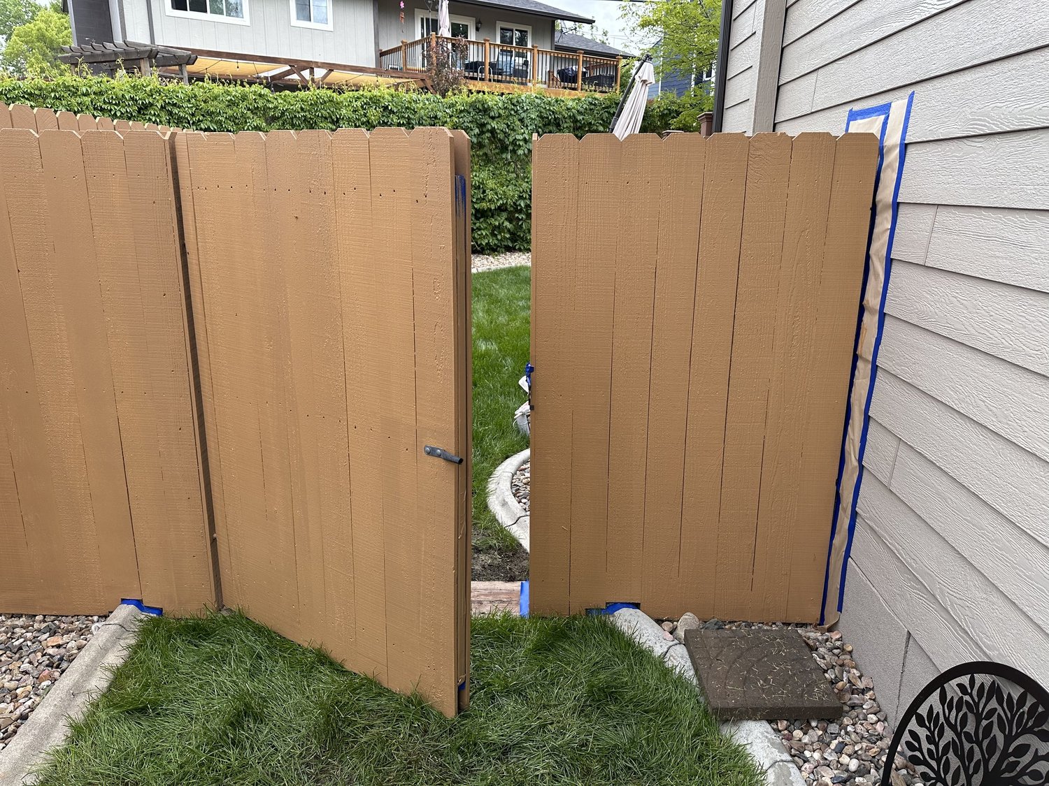 Outdoor wood fence and gate being painted warm brown